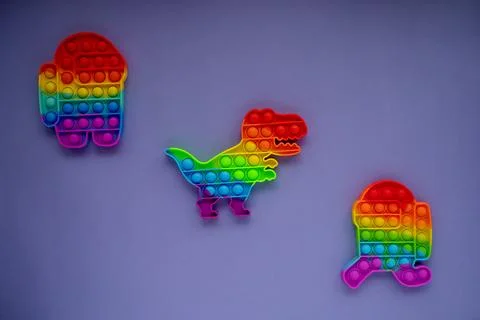 Trendy pop it and simpl dimple toys in form of dinosaur, and a character amon Stock Photos