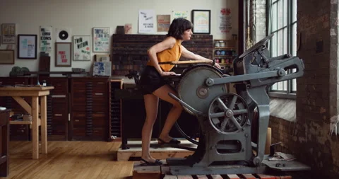 Trendy print maker walking to her letterpress machine and creating a print in in Video stock 199455825