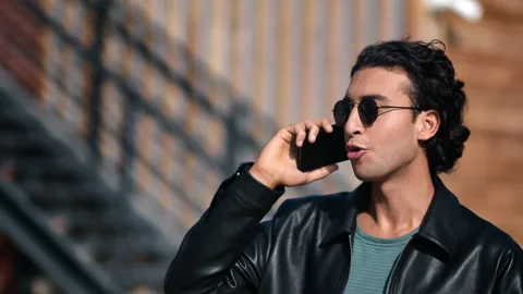 Trendy Spanish guy smiling talking smartphone sunny outdoor wooden building 動画素材 219960237