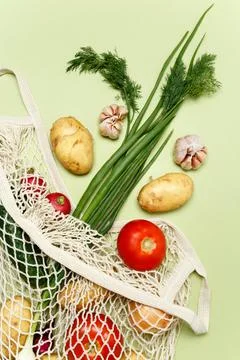 Trendy string bag with fresh vegetables and greens over light green backgroun Foto stock