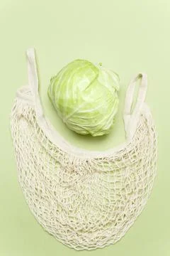 Trendy string bag with fresh young cabbage over light green background, zero  Foto stock