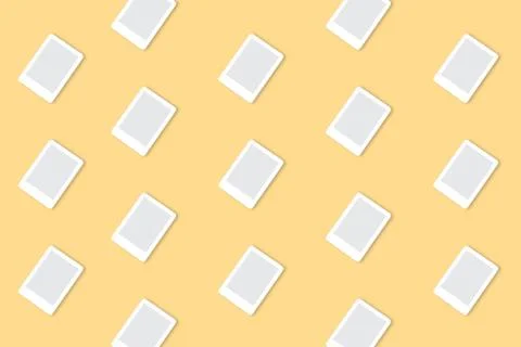 Trendy technological pattern made with white e-book on bright light yellow ba Stock Photos