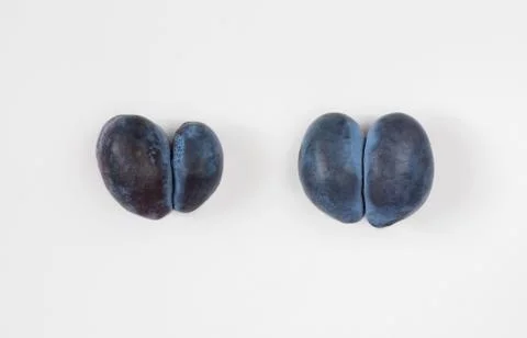 Trendy ugly food concept. Two purple plums on a white background. Stock Photos