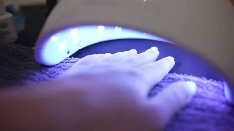Trendy UV led lamp for drying gel nail polish, female hand under the ultraviolet Stock Footage 233247145