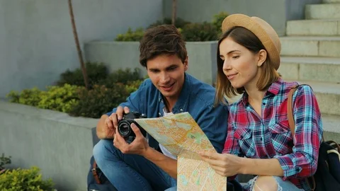 Trendy young couple using a local map on sunny day, caucasian man is holding a Stock Footage 80799026