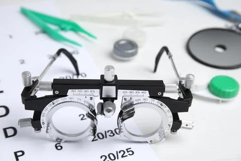 Trial frame with different ophthalmologist tools on white background, closeup Stock Photos