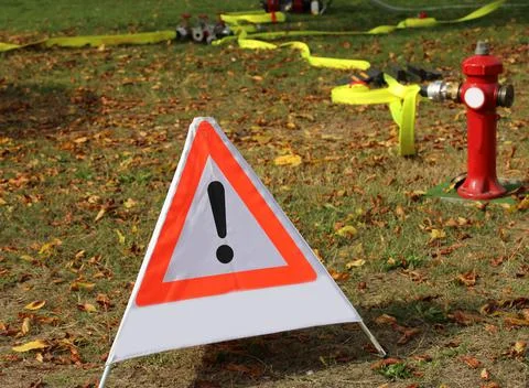 Triangle with exclamation mark and a red fire hydrant Stock Photos
