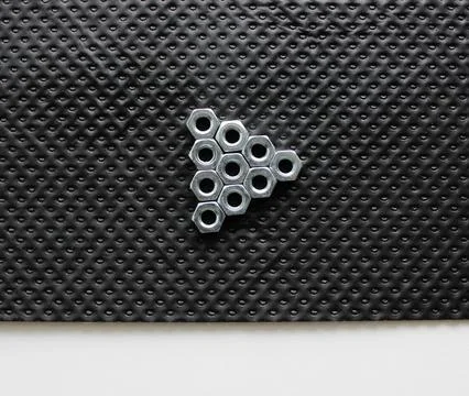 Triangle Made By Shiny Hex Nuts On A Black Plastic Sheet Stock Photos