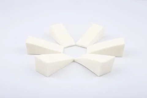 Triangle shaped make up sponges arranged in a circle on white background Stock Photos