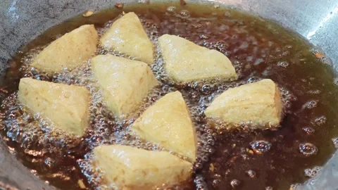 Triangle shaped white tofu deep frying in hot boiling oil. Stock Footage 344558040