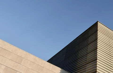 Triangle side corner of wide minimal building backlit by sun in suburban dist Stock Photos