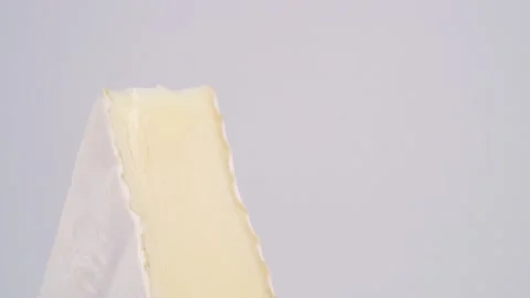 Triangle, a slice of white brie cheese on a wooden cutting board on a white b Stock Footage 155149518