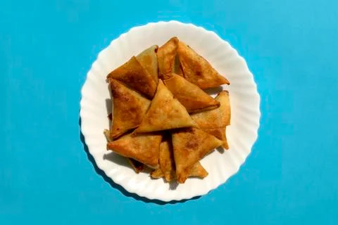 Triangular Arabic chicken samosa on bright blue background Foto stock