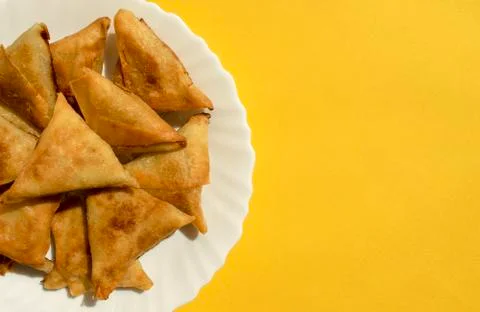 Triangular Arabic chicken samosa on yellow background with copy space Stock Photos