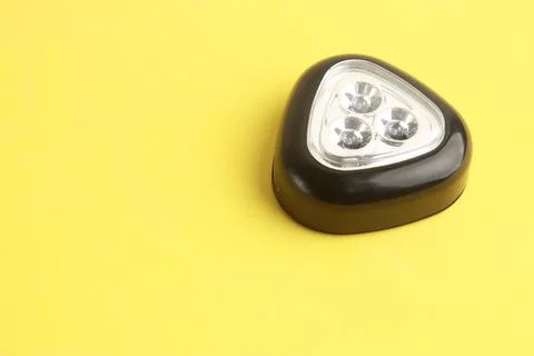 Triangular black flashlight on a yellow surface Stock Photos