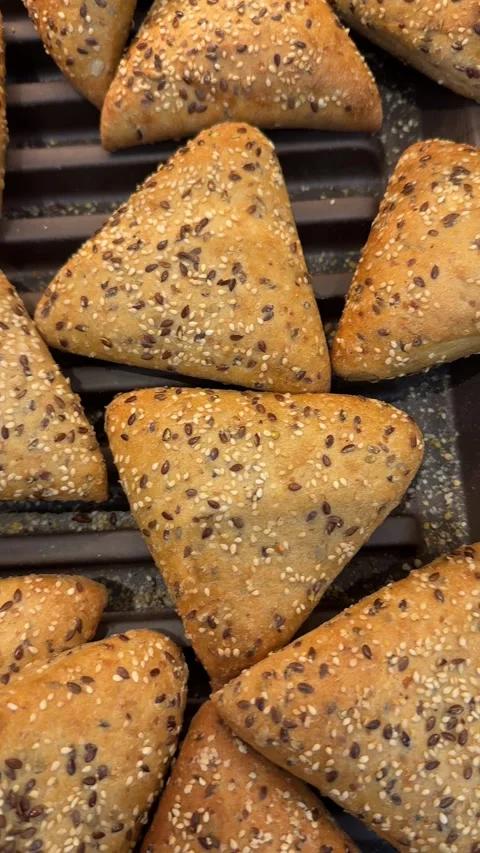 Triangular bread rolls with seeds arranged in bakery tray Stock Footage 317321309