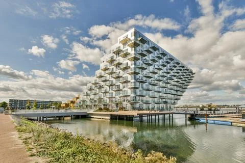 A triangular building on the water next to a river Stock Photos