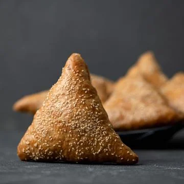Triangular buns with sesame seeds on gray blurred background. Fresh baking, Copy Stock Photos