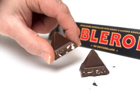 Triangular chocolate bar by Toblerone compagny in hand on white background 写真素材
