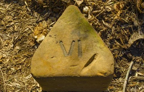 A triangular concrete stone with the sign of the Roman numeral four. Sign VI 库存照片