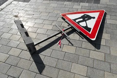 Triangular construction sign lies Fallen on road work urban street renovati.. Stock Photos