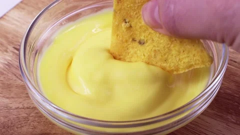 Triangular corn chips, Mexican nachos dips with creamy cheese sauce, close up Stock Footage 236143696