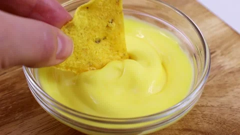 Triangular corn chips, Mexican nachos dips with creamy cheese sauce, close up Stock Footage 237254716