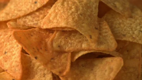 Triangular corn chips rotating on dark surface, nachos, geometric snack Stock Footage 327579725