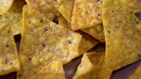Triangular corn nacho chips with seasoning rotating in a pile, macro close-up Stock Footage 345610784