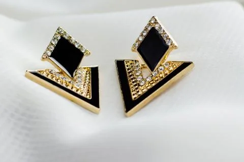 Triangular earrings on white fabric Fotos Stock
