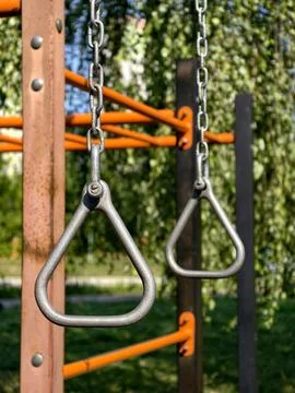 Triangular exercise handles suspended on metal chains in an outdoor park fo.. Stock Photos