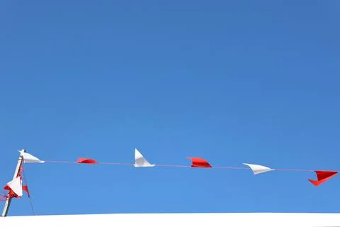 Triangular flag, red and white, when the wind blows on blue sky Stock Photos