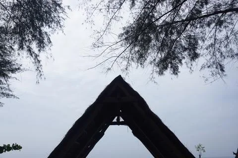 A triangular gazebo roofed with palm leaves, photo from the front Stock Photos