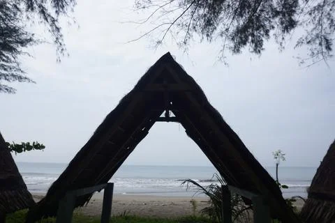 A triangular gazebo roofed with palm leaves, photo from the front Stock Photos