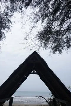A triangular gazebo roofed with palm leaves, photo from the front Stock Photos
