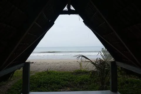 A triangular gazebo roofed with palm leaves, photo from the front Stock Photos