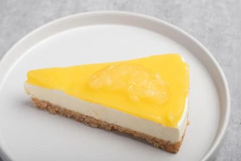 Triangular lemon cheesecake on a white plate Stock Photos