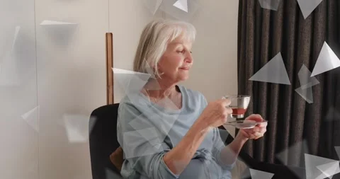 Triangular overlays drifting on screen guiding senior woman lifting glass teacup Stock Footage 320416029