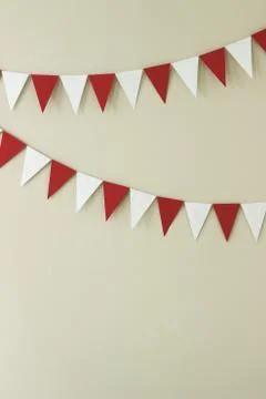 Triangular paper handmade garlands of white and red on a light wall. 스톡 사진