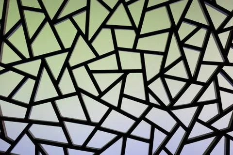 Triangular patterned surface on the wall that has art and sunlight through 스톡 사진
