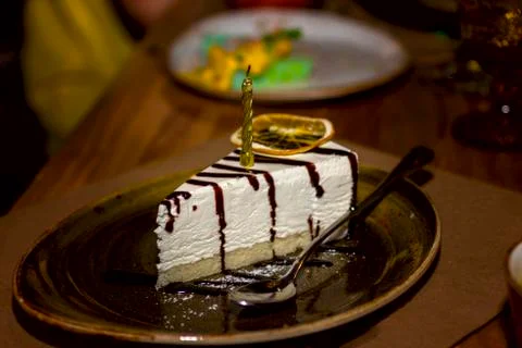 A triangular piece of cheesecake watered with a gold candle birthday gift Stock Photos