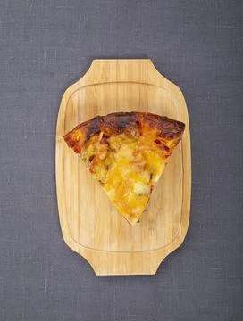 Triangular piece of pizza with cheese and pepperoni on a wooden pallet Stock Photos