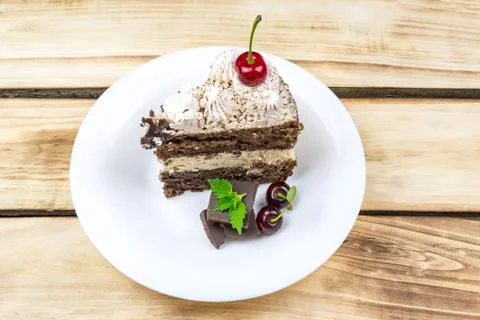 Triangular piece of Tiramisu cake on a white plate, a piece of chocolate. Foto stock