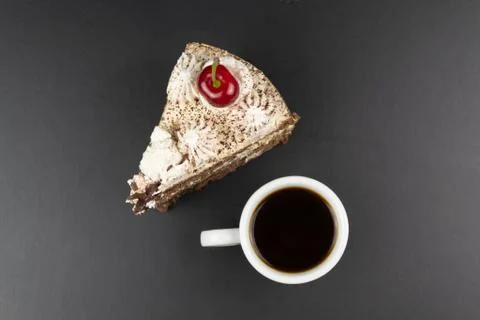 A triangular piece of tiramisu, decorated with cherries, a cup of coffee. Stock Photos