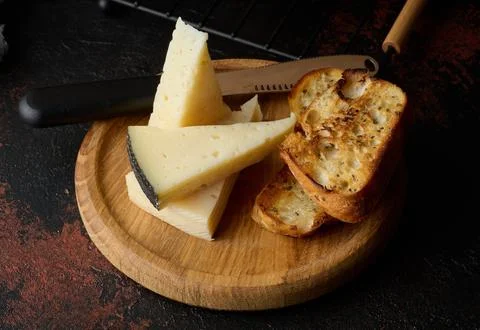 Triangular pieces of cheese and fried ciabatta slices on a wooden board 스톡 사진