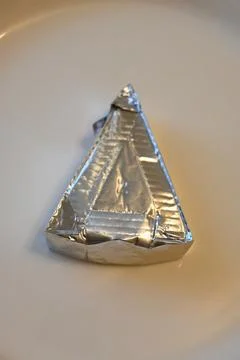 Triangular processed cheese portion in foil wrapper Stock Photos