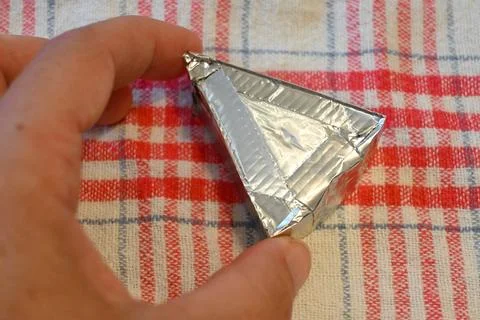 Triangular processed cheese portion in foil wrapper Stock Photos