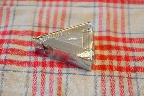 Triangular processed cheese portion in foil wrapper Фото