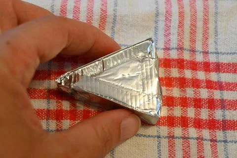 Triangular processed cheese portion in foil wrapping Stockfoto's