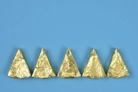 Triangular processed cheese portions in gold foil Fotos de archivo